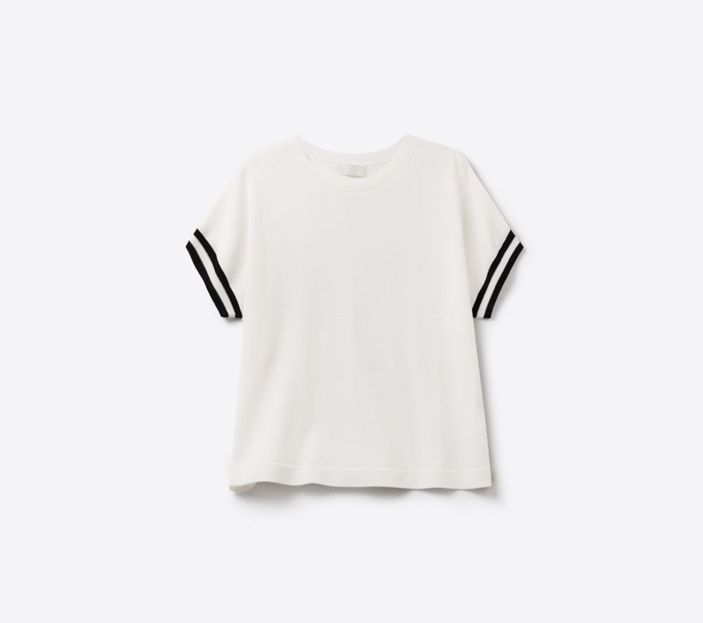 A white lightweight sweater with black sleeves and black stripes on the cuffs laid out flat against a white background.